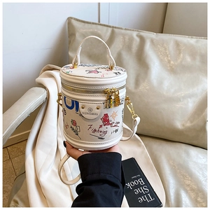Detail of white cylinder bucket bag with colorful graffiti and gold metal hardware