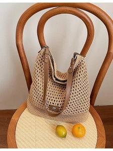 Grand sac de plage en tricot ajouré avec bandoulière en cuir sur une chaise en bois