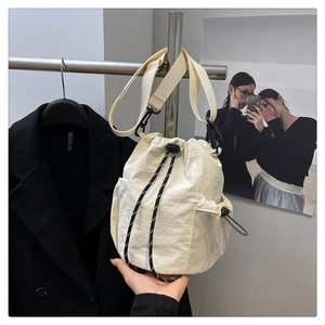 Detailansicht der cremefarbenen Nylon-Beuteltasche mit Netz-Seitentasche und Gurt