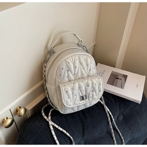 Detailed macro view of white quilted mini backpack with rhinestone studs and silver turn-lock