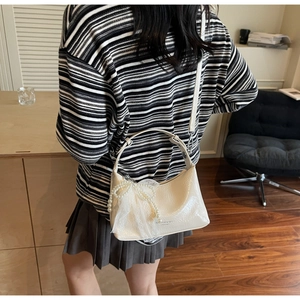 Sac bandoulière en cuir blanc crème avec nœud en perles et dentelle porté par mannequin