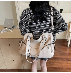 Détail du sac de style motard beige en cuir grainé avec une large bandoulière réglable