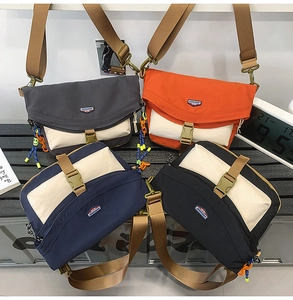 Group display of four nylon crossbody bags in black, orange, grey and navy blue