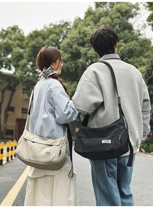 Outdoor shot of beige and black nylon crossbody bags showing casual utility style
