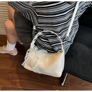Détail du sac en cuir blanc crème avec nœud en perles, dentelle et fini texturé