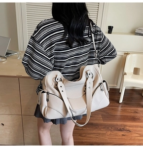 Détail du grand sac cabas clouté crème en cuir grainé avec vue sur la poche latérale