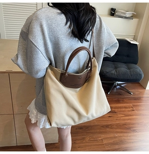 Canvas tote bag with brown leather straps shown on shoulder in a modern home setting
