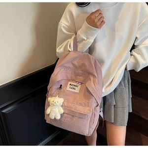 Dettaglio dello zaino in nylon viola chiaro con ricamo e ciondolo a forma di orso