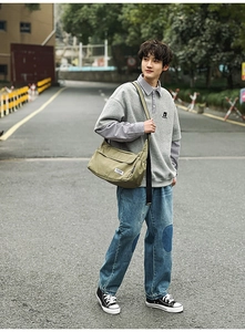 Close-up of military green canvas messenger bag with a white minimalist square brand logo