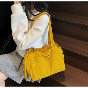 Detailed view of yellow nylon tote bag featuring drawstring closure and side pockets