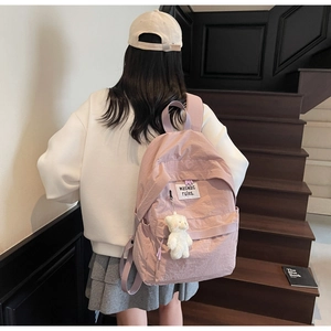 Zaino in nylon rosa con portachiavi a forma di orso bianco su scale moderne