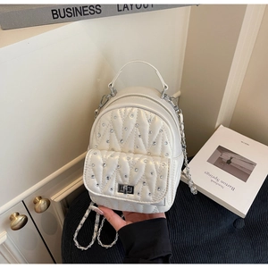 Detail of white quilted backpack with rhinestones, silver lock and chain straps