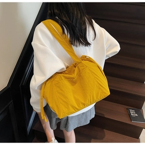 Close-up of bright yellow large nylon shoulder bag featuring side pockets and ruffles