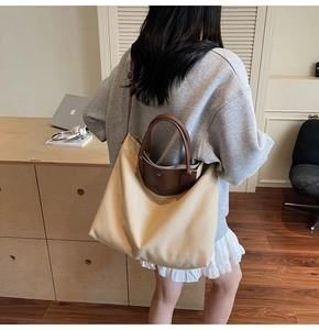Close-up of a large canvas tote bag with leather handles shown in an office setting