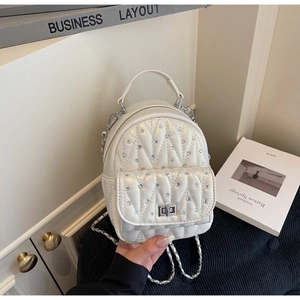 Detail of white quilted mini backpack with rhinestone studs and silver chain strap