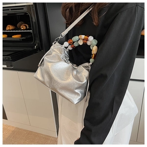 Detail of silver pleated bucket bag featuring a colorful beaded handle and fine texture