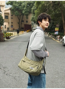 Outdoor shot of an olive green nylon messenger bag showing spacious capacity and fit