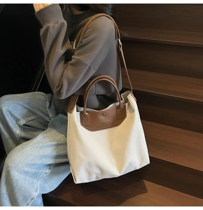 Lifestyle view of large beige canvas tote bag with brown leather trim on stairs