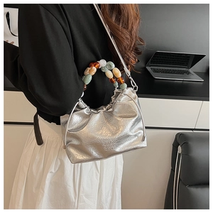 Chic silver pleated bucket bag with vibrant acrylic beaded handle shown on model