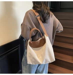 Close-up of cream canvas tote bag with brown leather handles and a wide shoulder strap