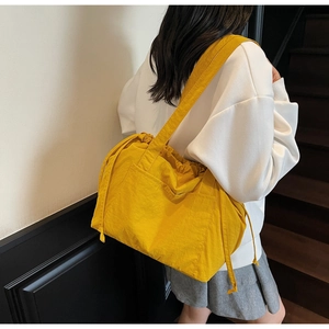 Detailed view of the bright yellow nylon shoulder bag with drawstring and side pocket