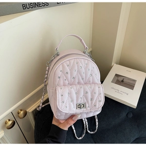 Detail of pink quilted backpack featuring diamond-studded pattern and silver chain straps