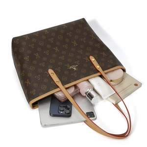 Flat lay of a large brown leather tote bag showing spacious interior with laptop and books