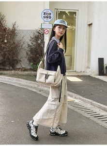 Detail of off-white nylon crossbody bag featuring double front pockets and zipper design