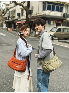 Detail of nylon messenger bags in orange and olive green with wide adjustable straps