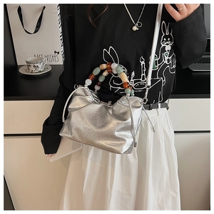 Close-up of silver pleated bucket bag featuring a colorful beaded handle and metallic finish