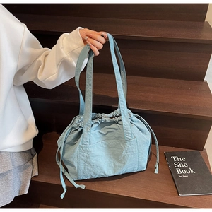 Detail of light blue nylon drawstring tote bag on wooden stairs in a lifestyle setting