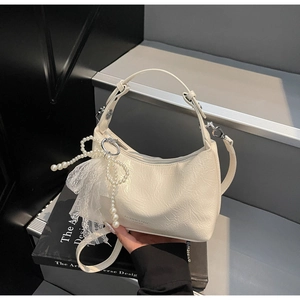 Détail du sac en cuir plissé blanc crème avec nœud en perles et pendentif en dentelle