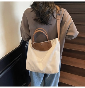 Model wearing a large canvas tote bag with brown leather handles on a staircase