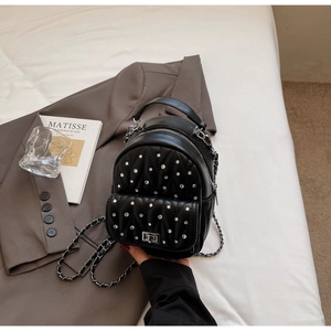 Close-up of black quilted mini backpack with rhinestone detailing and silver chain straps