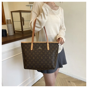 Detail of premium brown monogram tote bag showing brand lettering and textured leather material