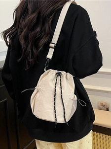 Beigefarbene Nylon-Beuteltasche mit verstellbarem Schultergurt, am Modell präsentiert