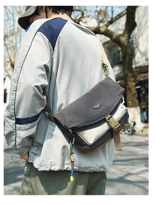 Close-up of a large nylon messenger bag showing the buckle closure and wide strap