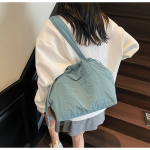 Close-up of teal nylon tote bag with drawstring closure and pleated texture detail