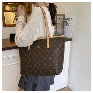 Detail of the stitching and golden brand logo on a dark brown monogram tote bag