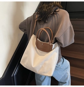 Detail showing the canvas tote bag with brown leather handles and brand lettering on stairs