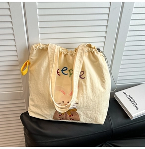 Detail of cream drawstring tote bag with cartoon rabbit and colorful eepe text