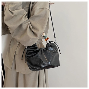 Detail view of black glossy drawstring bucket bag with colorful resin beaded handle strap