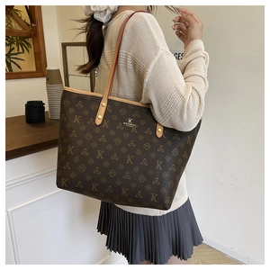 Detail of vintage monogram pattern and metal logo plate on dark brown tote bag