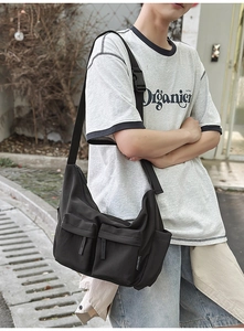 Detail of black nylon crossbody bag with dual front pockets and adjustable strap