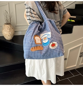 Detail of blue plaid canvas tote with afternoon tea appliques and drawstring closure