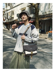 Detail of a large nylon crossbody bag with buckle closure in a street fashion style outfit