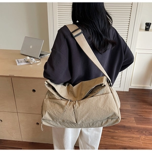 Detail einer khakifarbenen Messenger-Bag aus Nylon mit verstellbarem Schultergurt