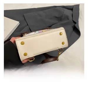 Detail view of the white leather bag bottom showing gold metal protective feet and stitching