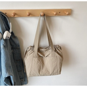 Detail of khaki nylon tote bag featuring drawstring closure and functional front pocket