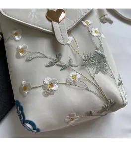 Détail de la broderie fleurie et du fermoir coeur doré sur le sac bandoulière